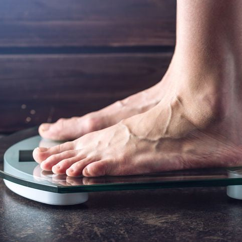 Female-feet-standing-on-electronic-scales-for-weight-control-on-dark-background.-Concept-of-sports-training,-diets-959543086_727x485